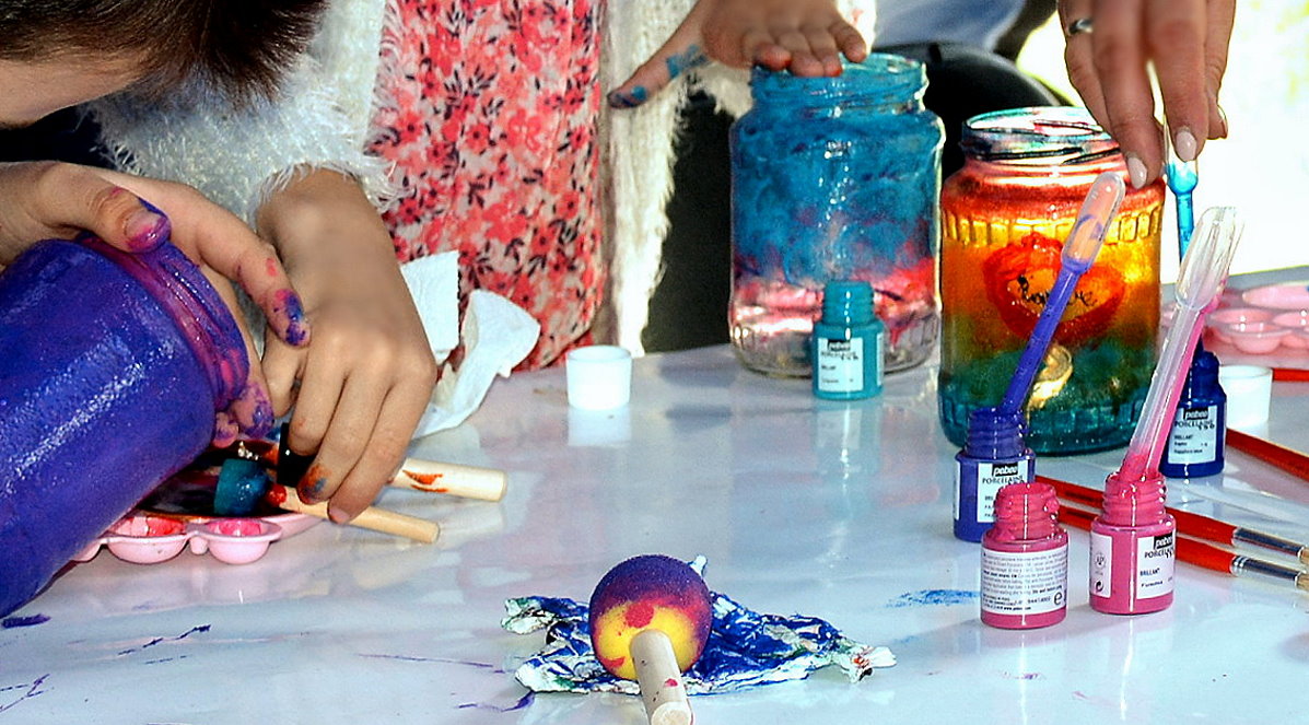 Kolorowe farby na stole i dłonie artystów.