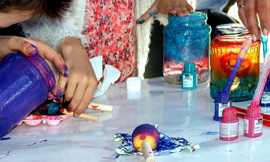 Kolorowe farby na stole i dłonie artystów.